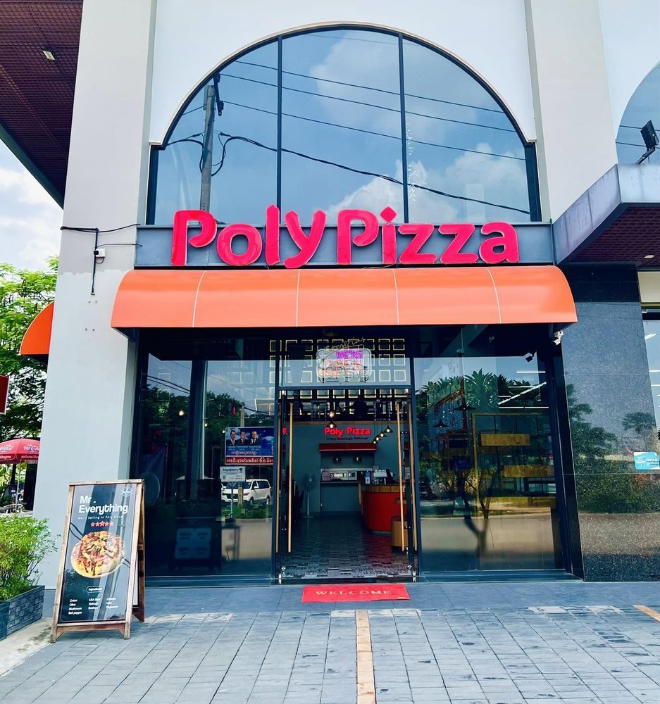 Poly Pizza storefront with orange awning next to Thai Huot Market in Sen Sok, Phnom Penh